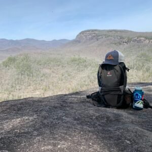 a backpack sitting on top of a rock next to a can of soda